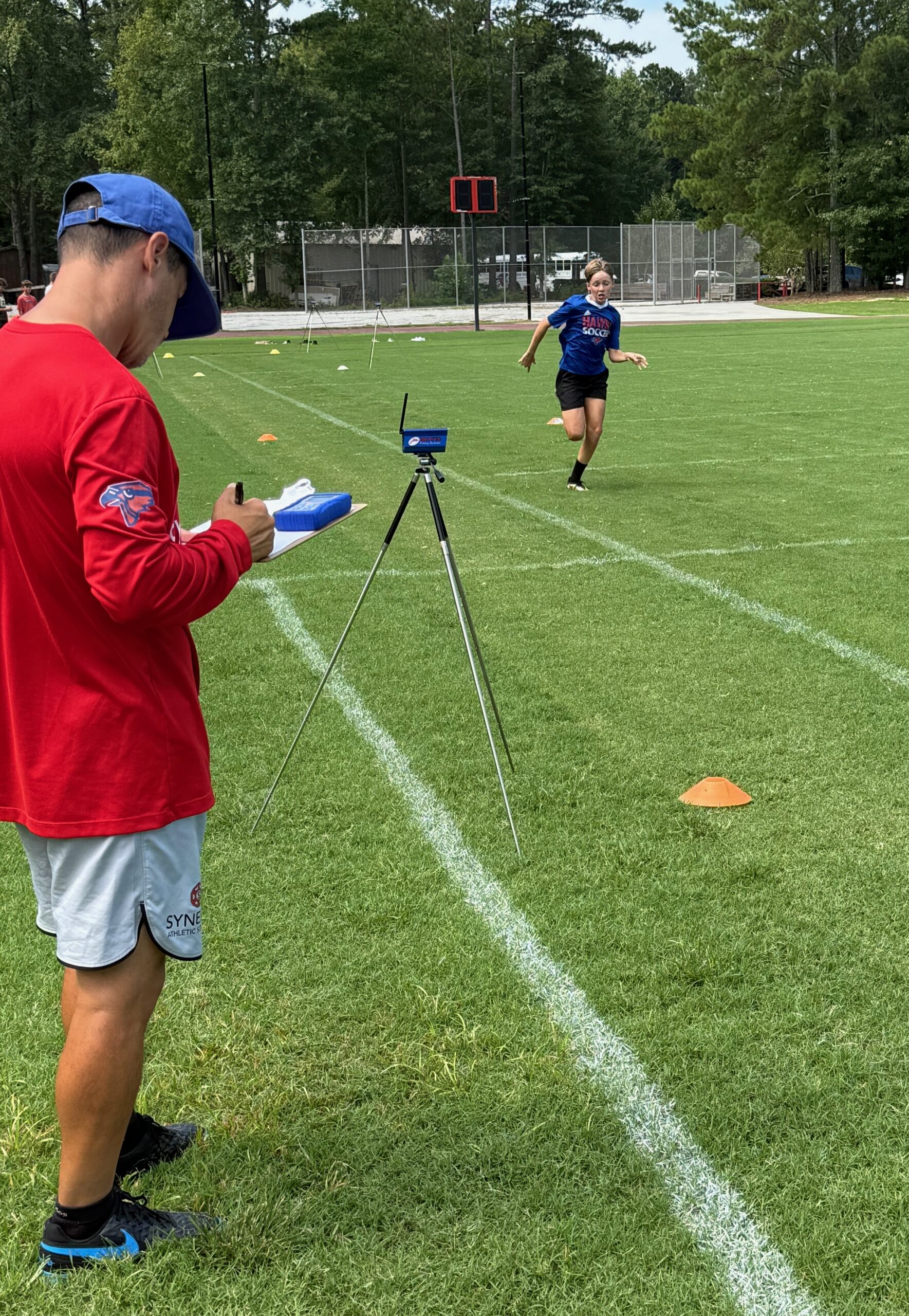 Soccer athlete completing a speed assessment while a coach collects performance testing data during a field evaluation.